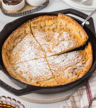 a Dutch baby pancake topped with powdered sugar in a cast iron skillet