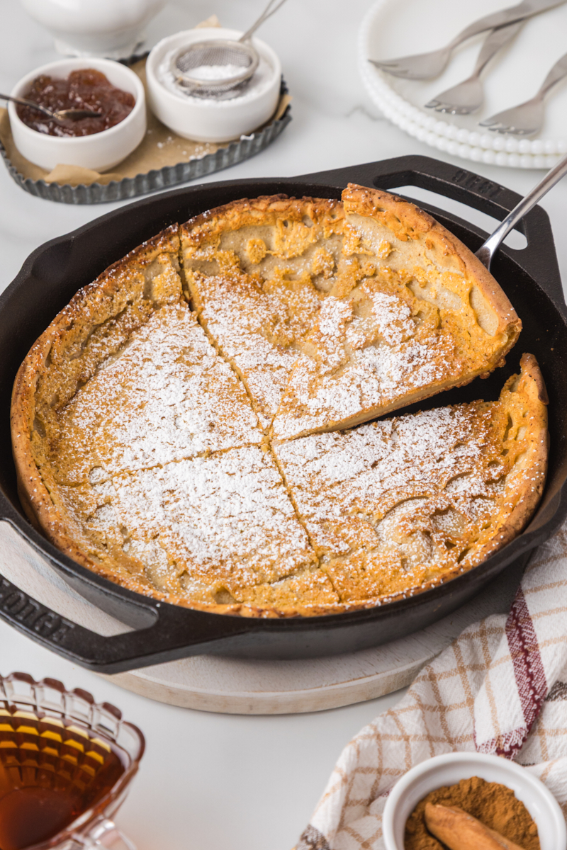 a Dutch baby pancake topped with powdered sugar in a cast iron skillet