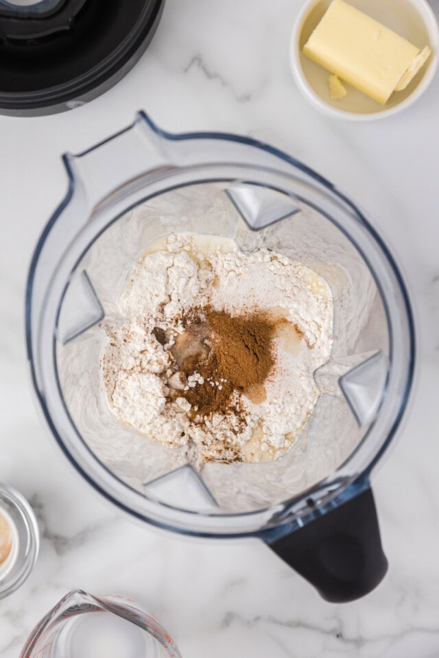 overhead view of eggs, flour, milk, sugar, cinnamon, vanilla, and salt in a blender
