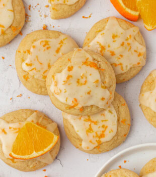 overhead view of glazed orange cookies scattered on a white surface