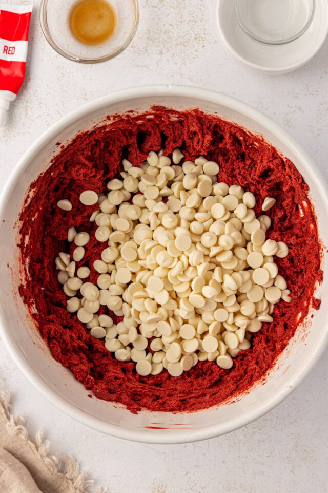 overhead view of white chocolate chips added to red velvet cookie batter