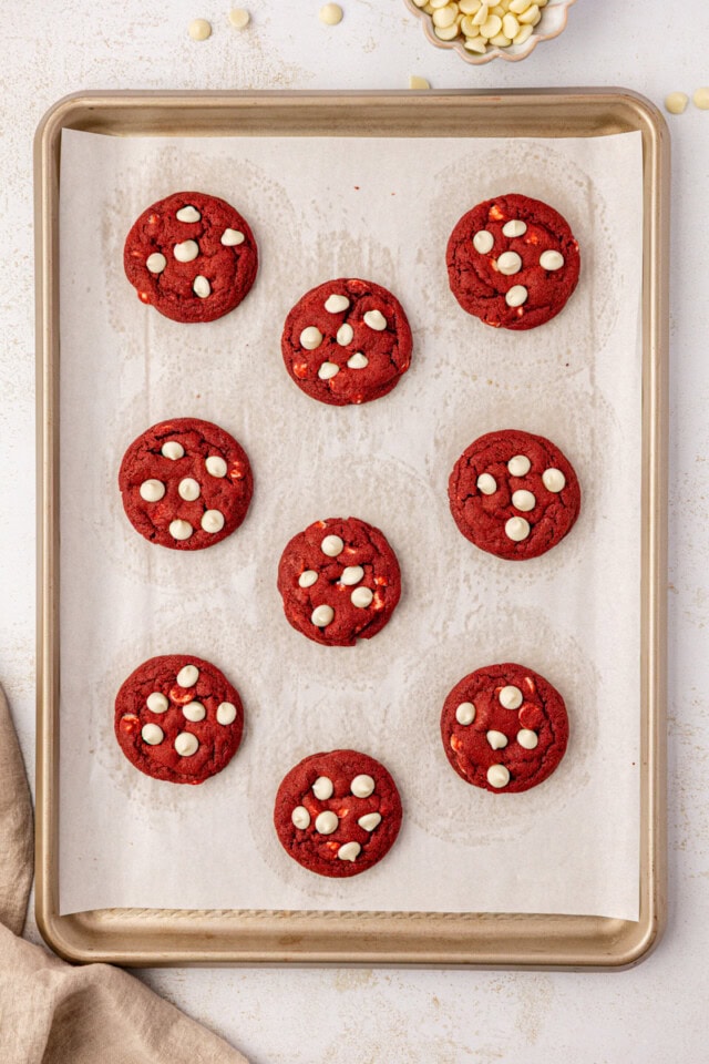overhead view of freshly baked red velvet cookies on a parchment-lined baking sheet