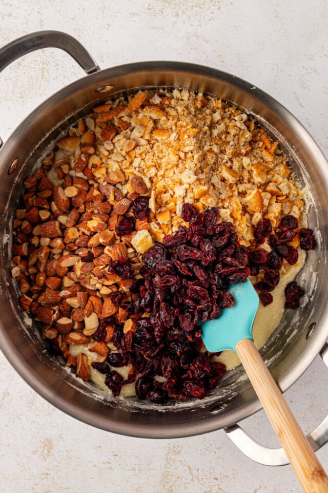 overhead view of crushed crackers, dried cranberries, and chopped nuts added to snowflake crisp mixture