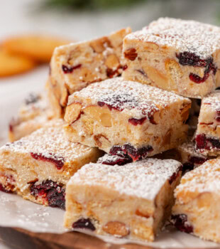 snowflake crisp made with white chocolate, dried cranberries, crackers, and nuts, and dusted with powdered sugar, served on a wooden tray