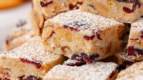 snowflake crisp made with white chocolate, dried cranberries, crackers, and nuts, and dusted with powdered sugar, served on a wooden tray