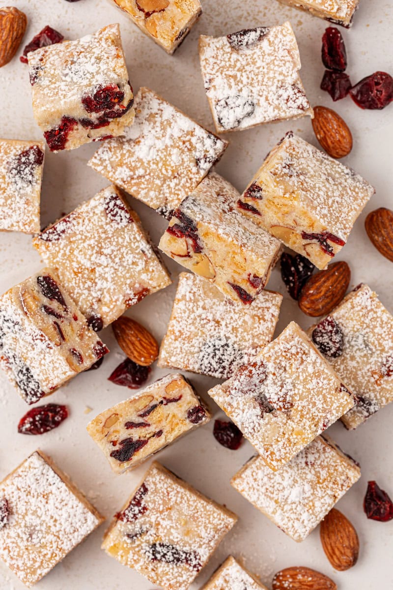 overhead view of snowflake crisp scattered on parchment paper with almonds and dried cranberries scattered alongside