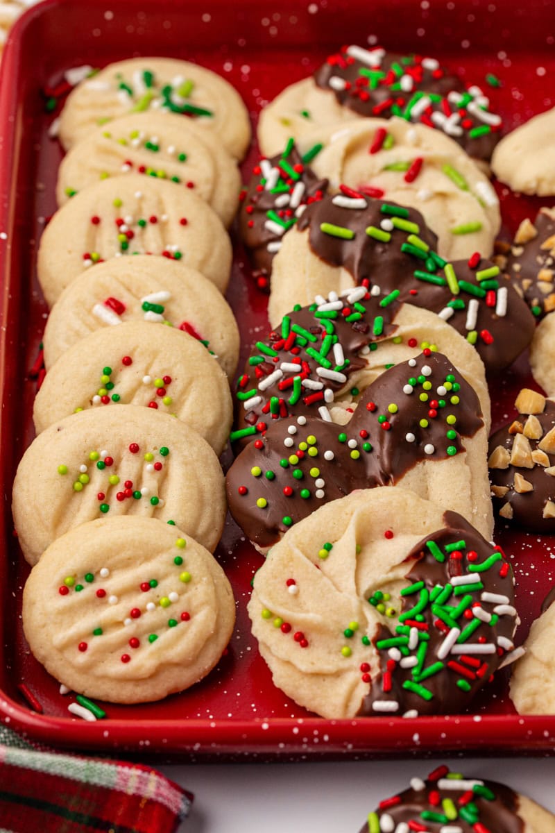whipped shortbread cookies arranged on a red tray, showing various shapes and garnishes