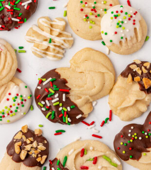 overhead view of whipped shortbread cookies in various styles such as s-swirls, rosettes, rounds, sprinkles, and chocolate-dipped