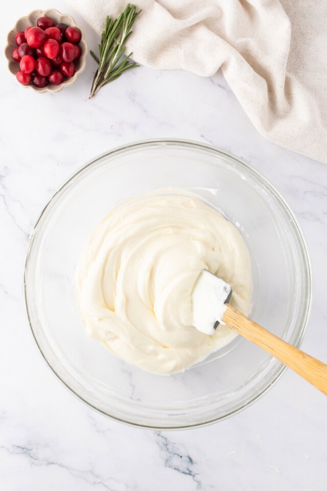overhead view of no-bake white chocolate cheesecake mixture in a glass mixing bowl