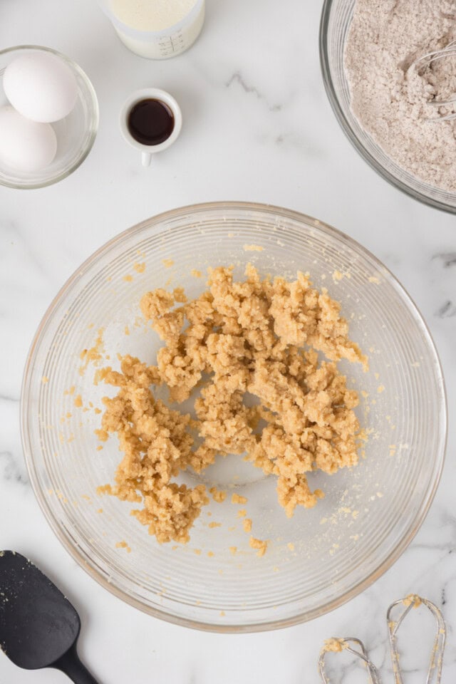 overhead view of creamed butter, sugar, and brown sugar in a glass mixing bowl