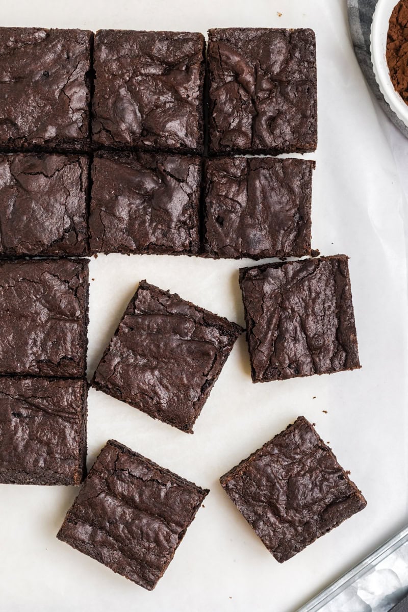 overhead view of sliced dark cocoa brownies on parchment paper