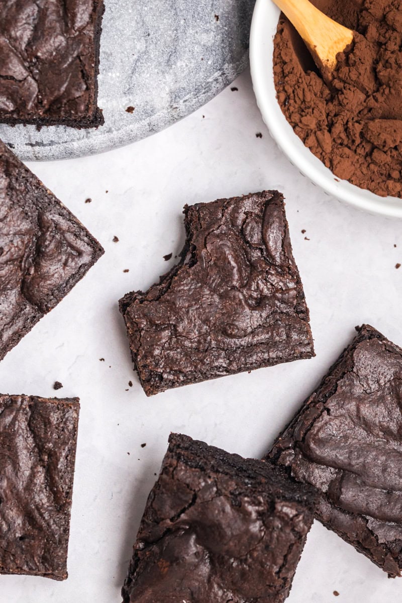 overhead view of several dark cocoa brownies on a white surface