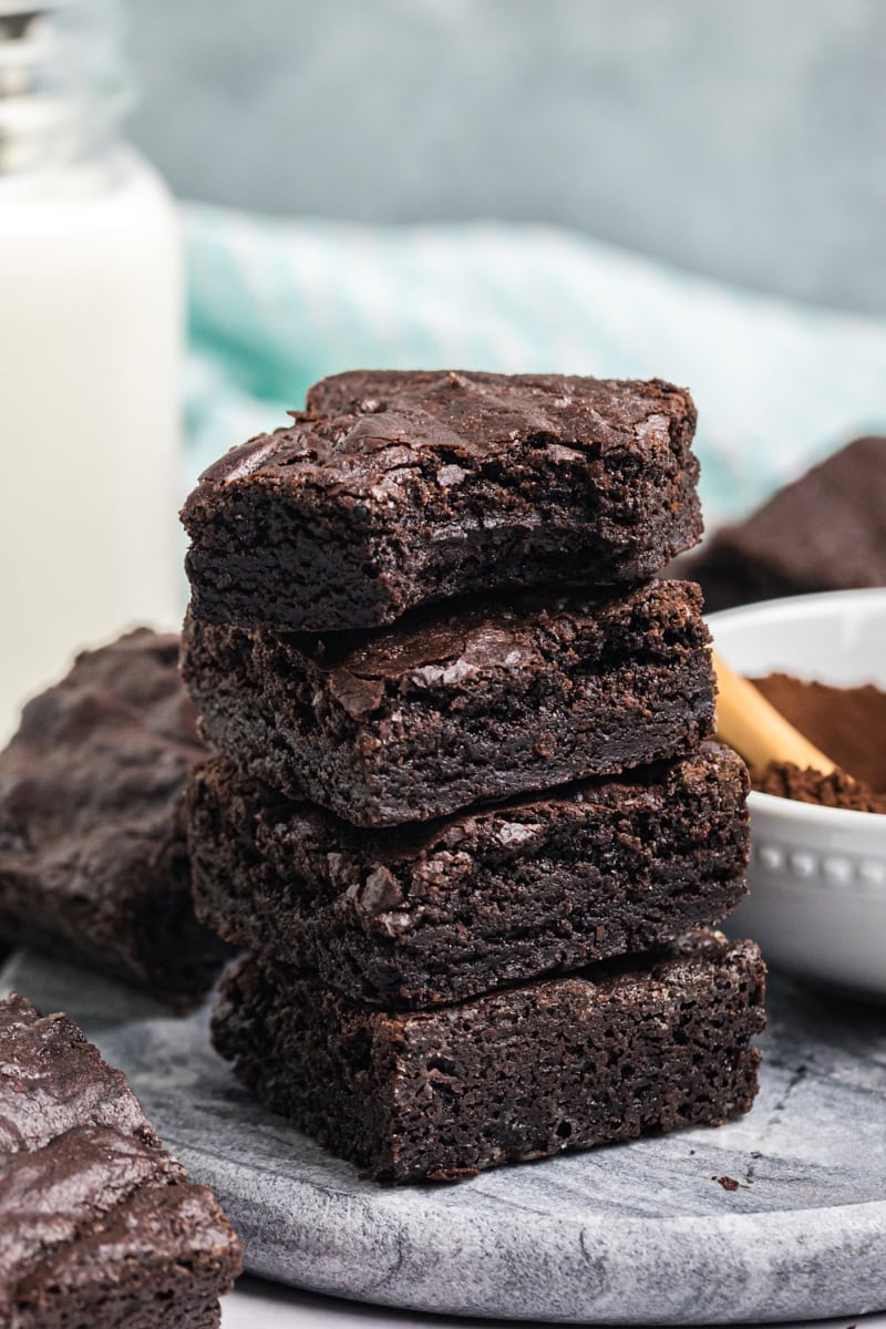 stack of four fudgy dark cocoa brownies with a bite missing from the top brownie