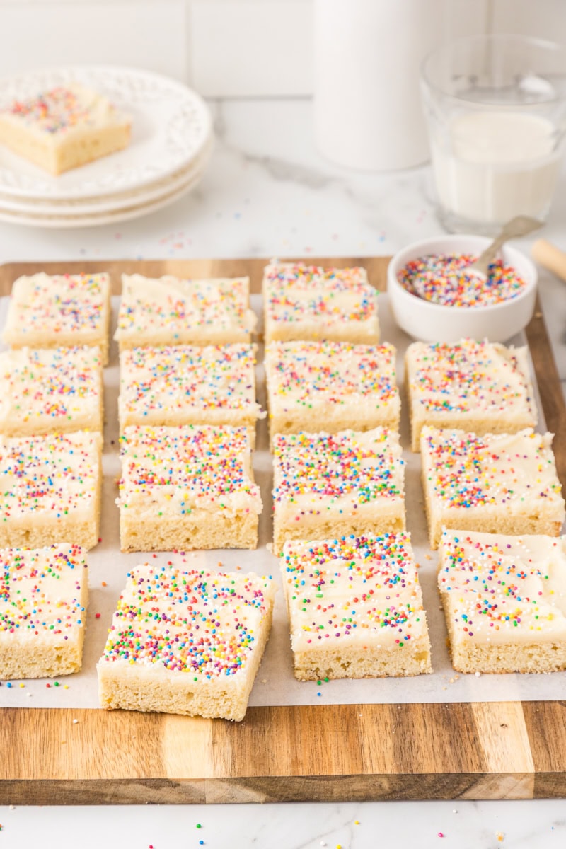 frosted sugar cookie bars on a wooden board