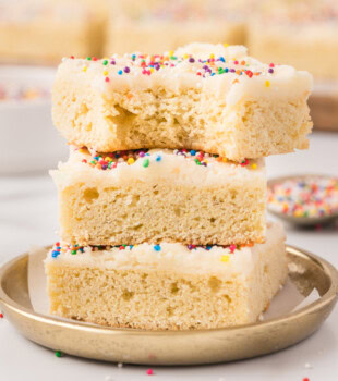 stack of three frosted sugar cookie bars with a bite missing from the top bar