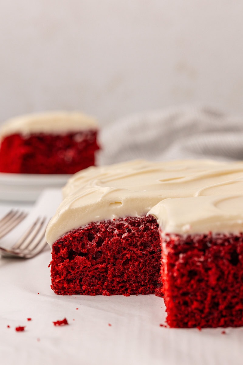 partially sliced red velvet sheet cake with cream cheese frosting