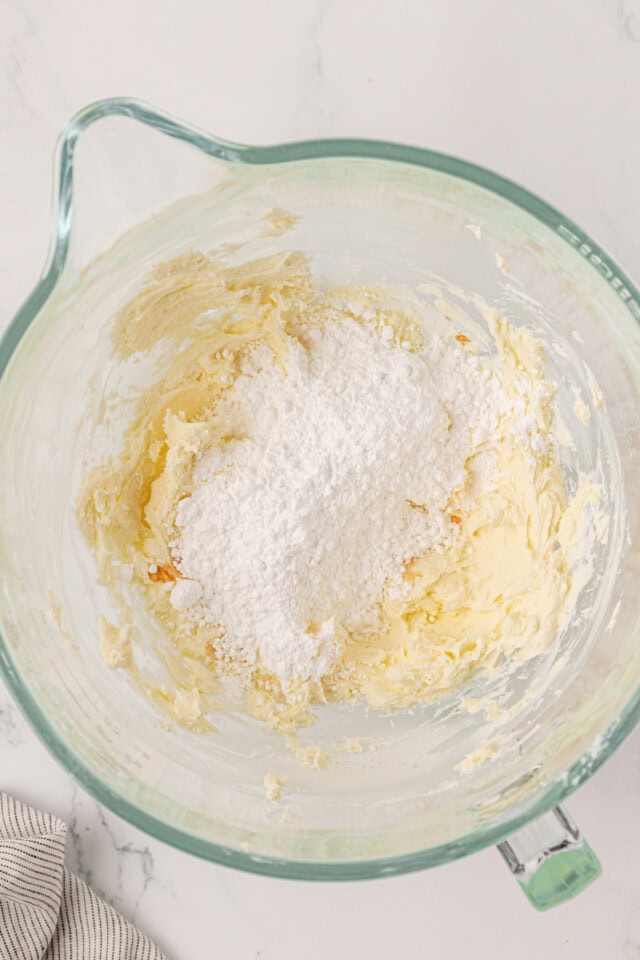 overhead view of confectioners' sugar added to frosting mixture