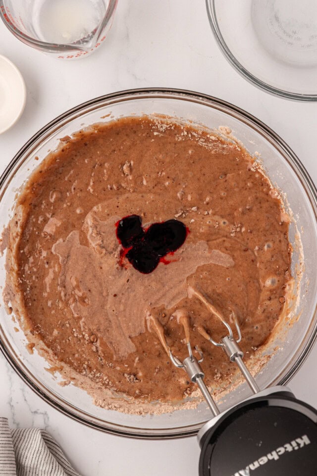 overhead view of red food coloring added to cake batter