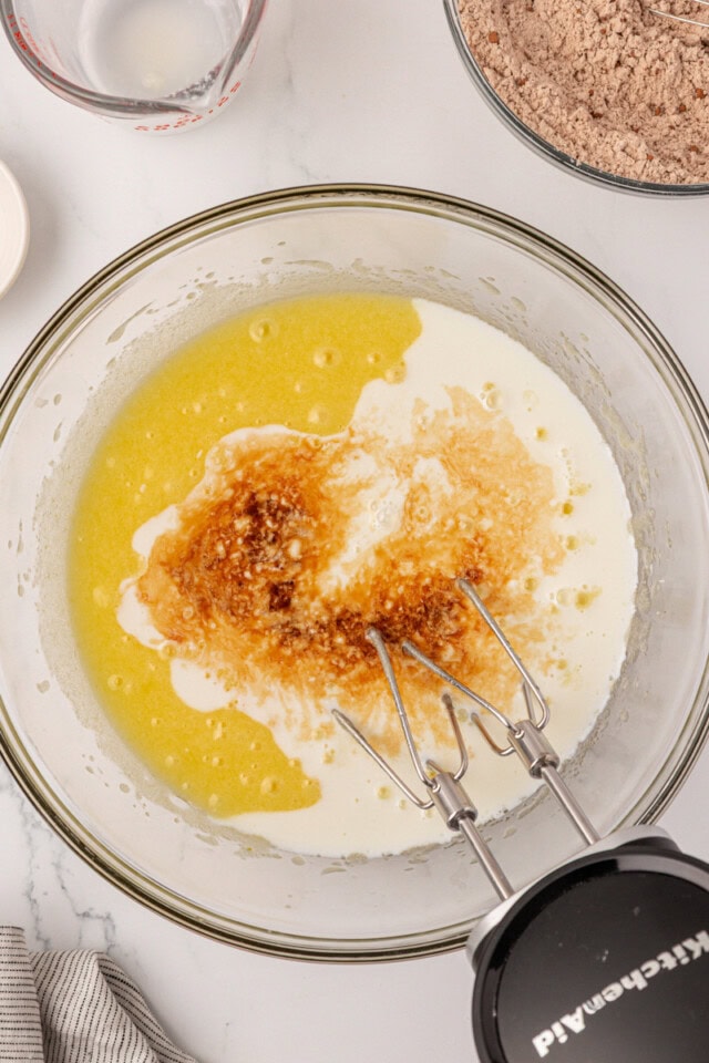 overhead view of buttermilk and vanilla added to beaten eggs, sugar, and oil in amixing bowl