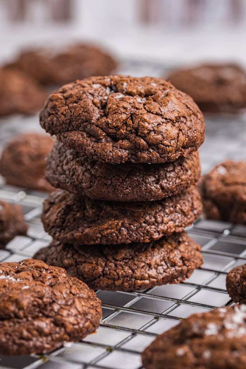 a stack of four salted chocolate truffle cookies surrounded by more cookies on a wire rack