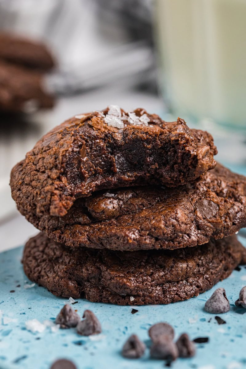 stack of three salted chocolate truffle cookies with a bite missing from the top cookie