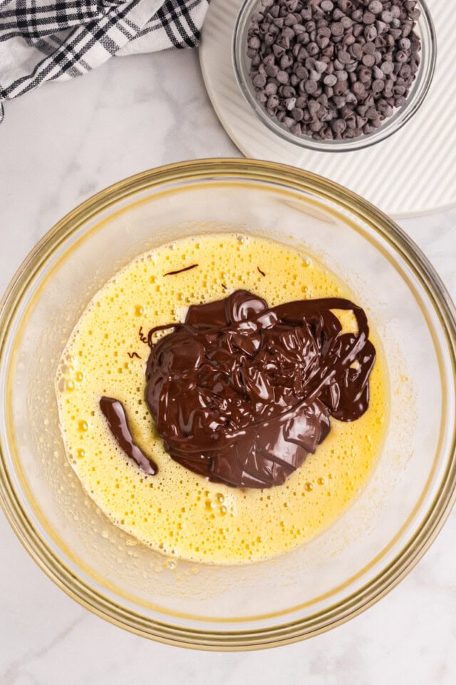 overhead view of melted chocolate mixture added to sugar-egg mixture in a mixing bowl