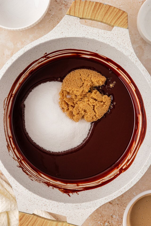 overhead view of sugar and brown sugar added to melted butter and chocolate