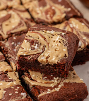 a tahini brownie resting on top of more brownies on parchment paper