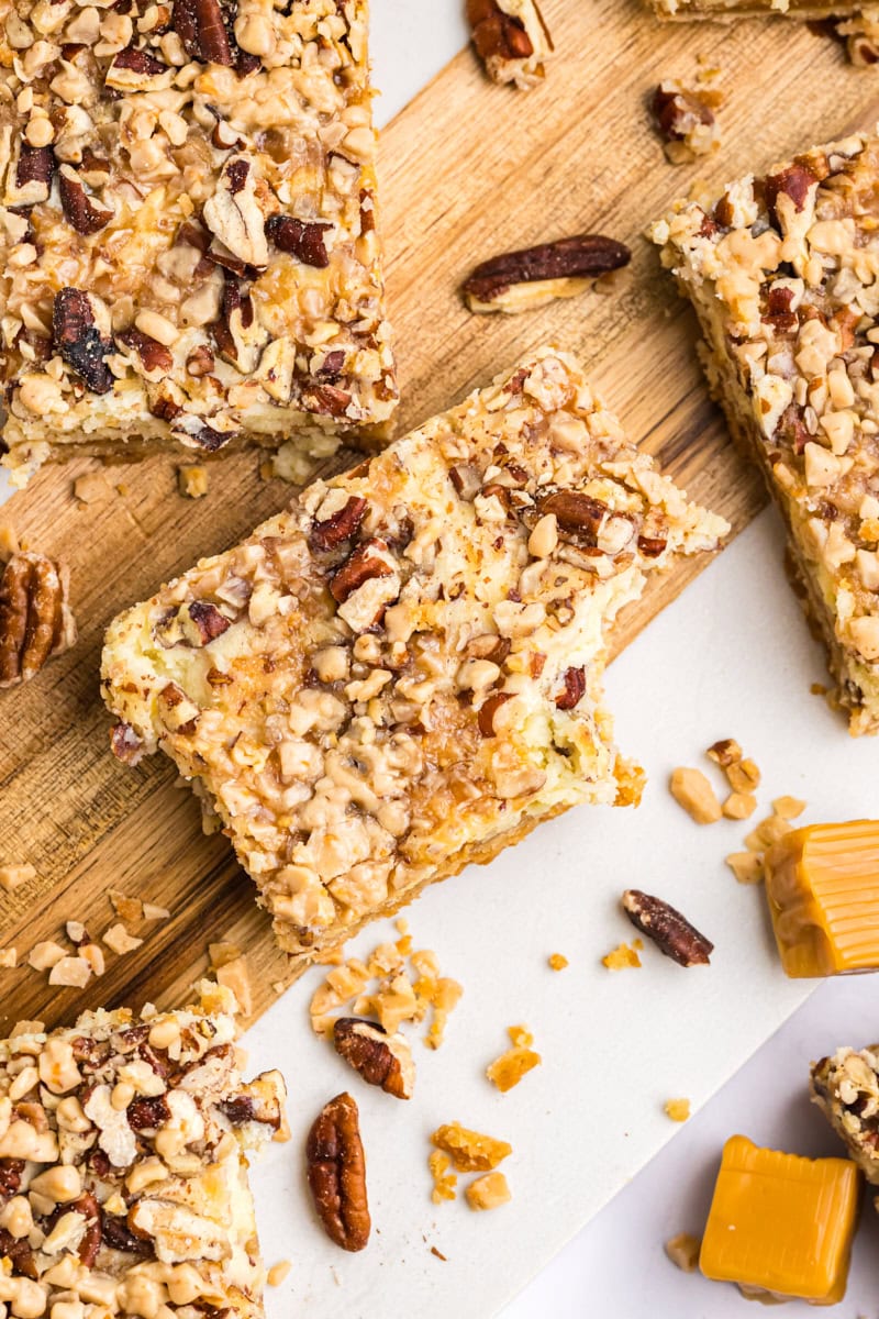 overhead view of caramel cheesecake bars on a wooden cutting board