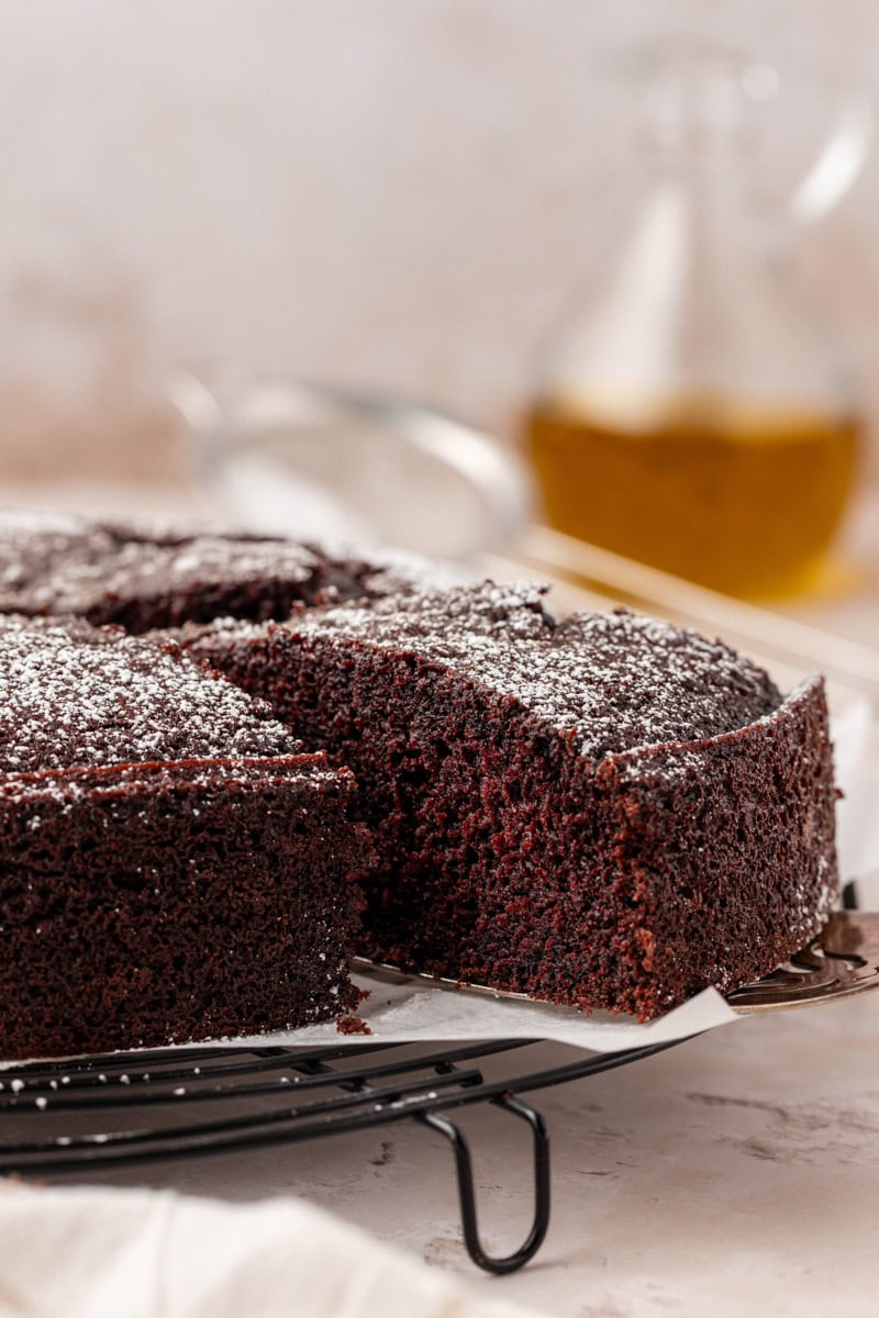 a slice of chocolate olive oil cake being removed from the remaining cake