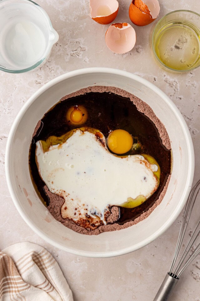 overhead view of olive oil, eggs, vanilla, and buttermilk in a mixing bowl