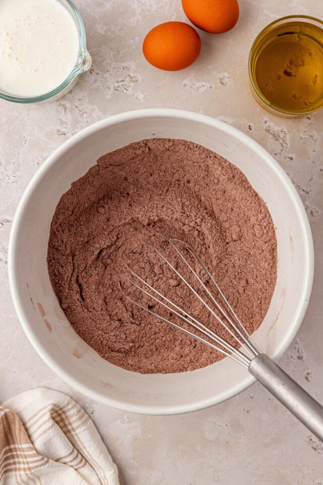 overhead view of flour, cocoa, sugar, brown sugar, baking soda, baking powder, and salt combined in a mixing bowl