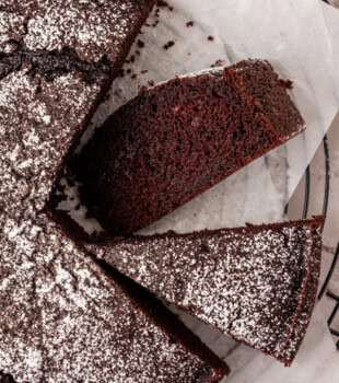 overhead view of partially sliced chocolate olive oil cake with a slice on its side to show the soft texture