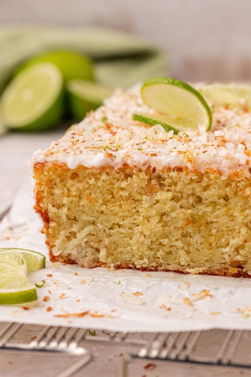 sliced coconut lime loaf cake topped with lime glaze and toasted coconut, showing a moist, tender crumb