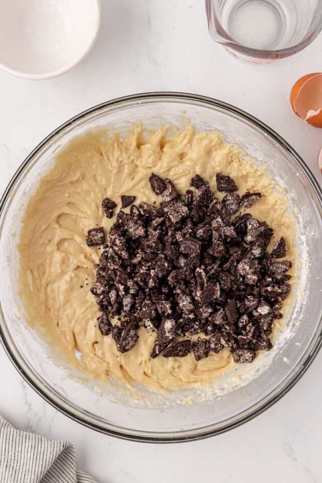 overhead view of chocolate sandwich cookie pieces added to vanilla cupcake batter