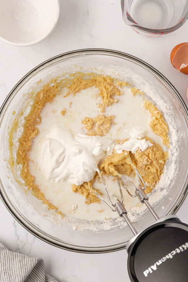 overhead view of milk and sour cream added to overhead view of dry ingredients added to wet ingredients for cookies and cream cupcake batter