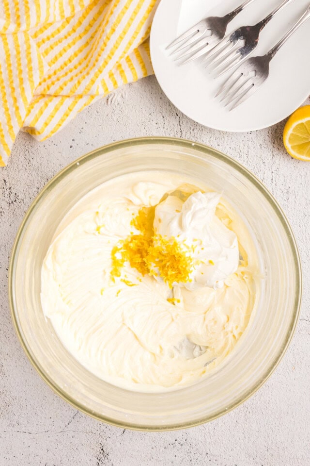 overhead view of sour cream and lemon zest added to frosting mixture