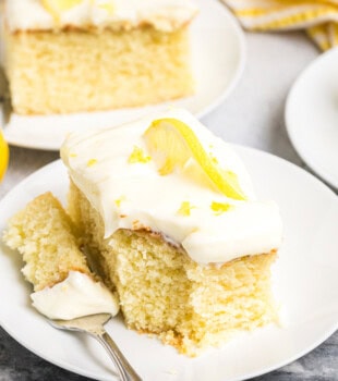 a slice of lemon sheet cake and a bite on a fork on a white plate