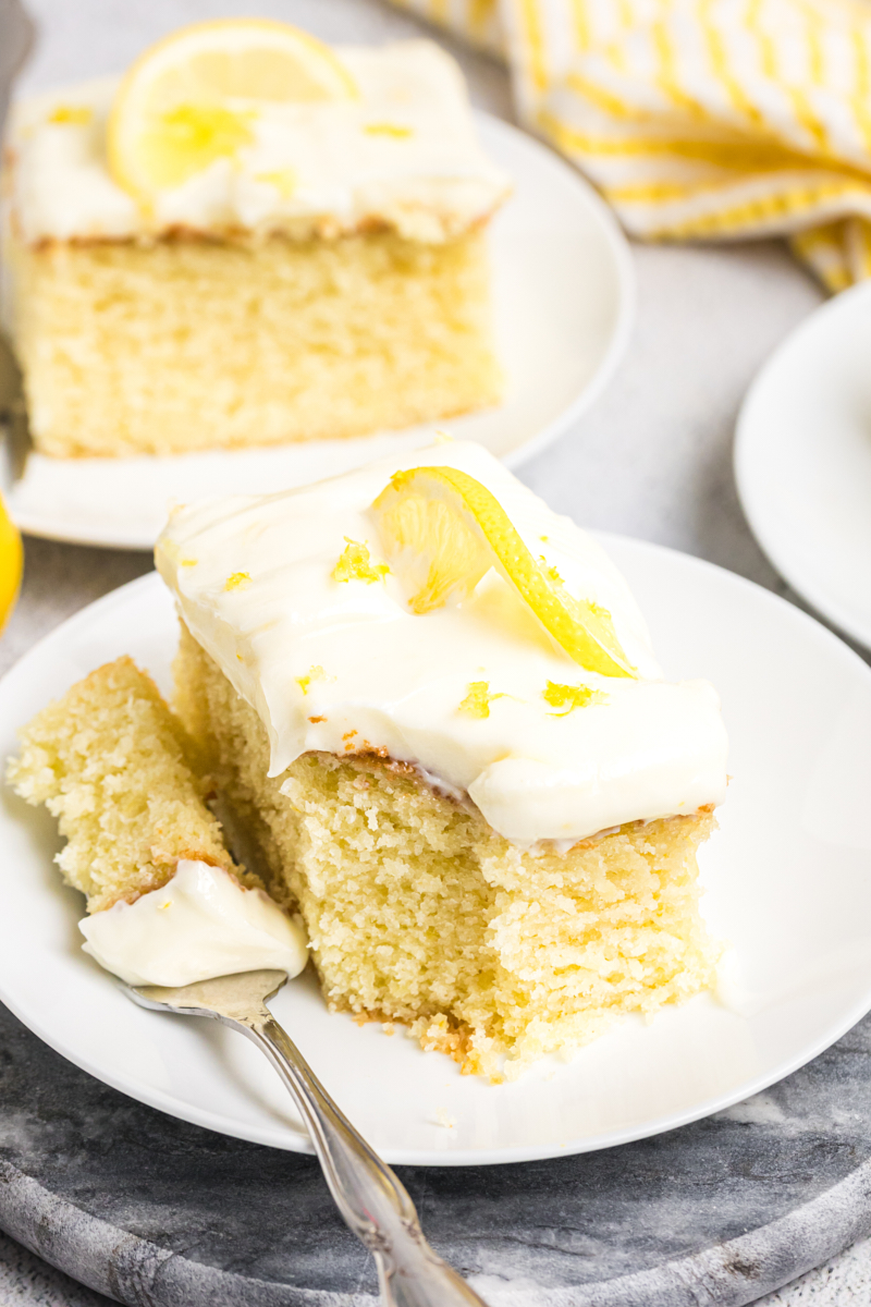 a slice of lemon sheet cake and a bite on a fork on a white plate