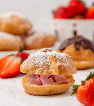 a profiterole filled with strawberry ice cream and topped with a sprinkling of powdered sugar