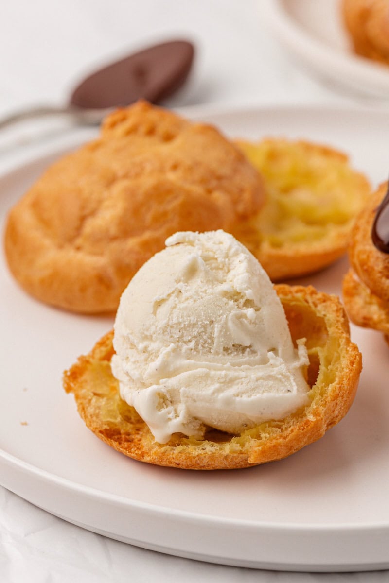 a scoop of vanilla ice cream placed on the bottom half of a profiterole