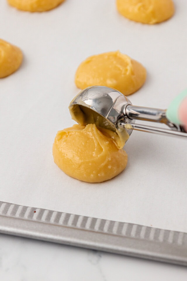 pâte à choux being portioned onto a parchment-lined baking sheet