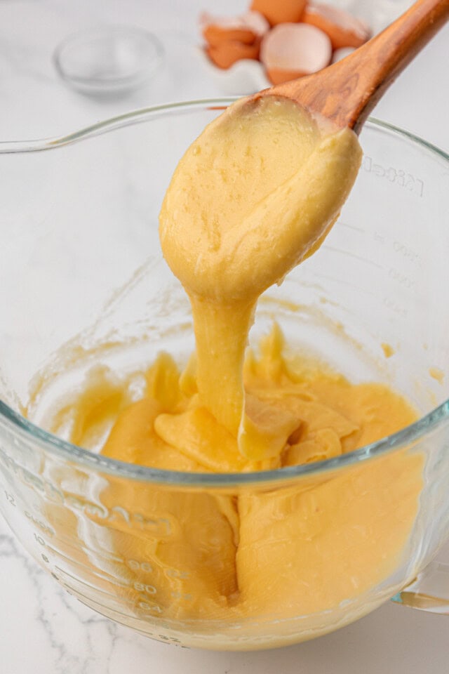 a wooden spoon lifting from pâte à choux to show the texture of the dough