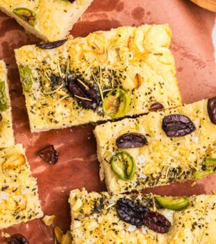 overhead view of slices of no-knead focaccia topped with herbs, cheese, and olives