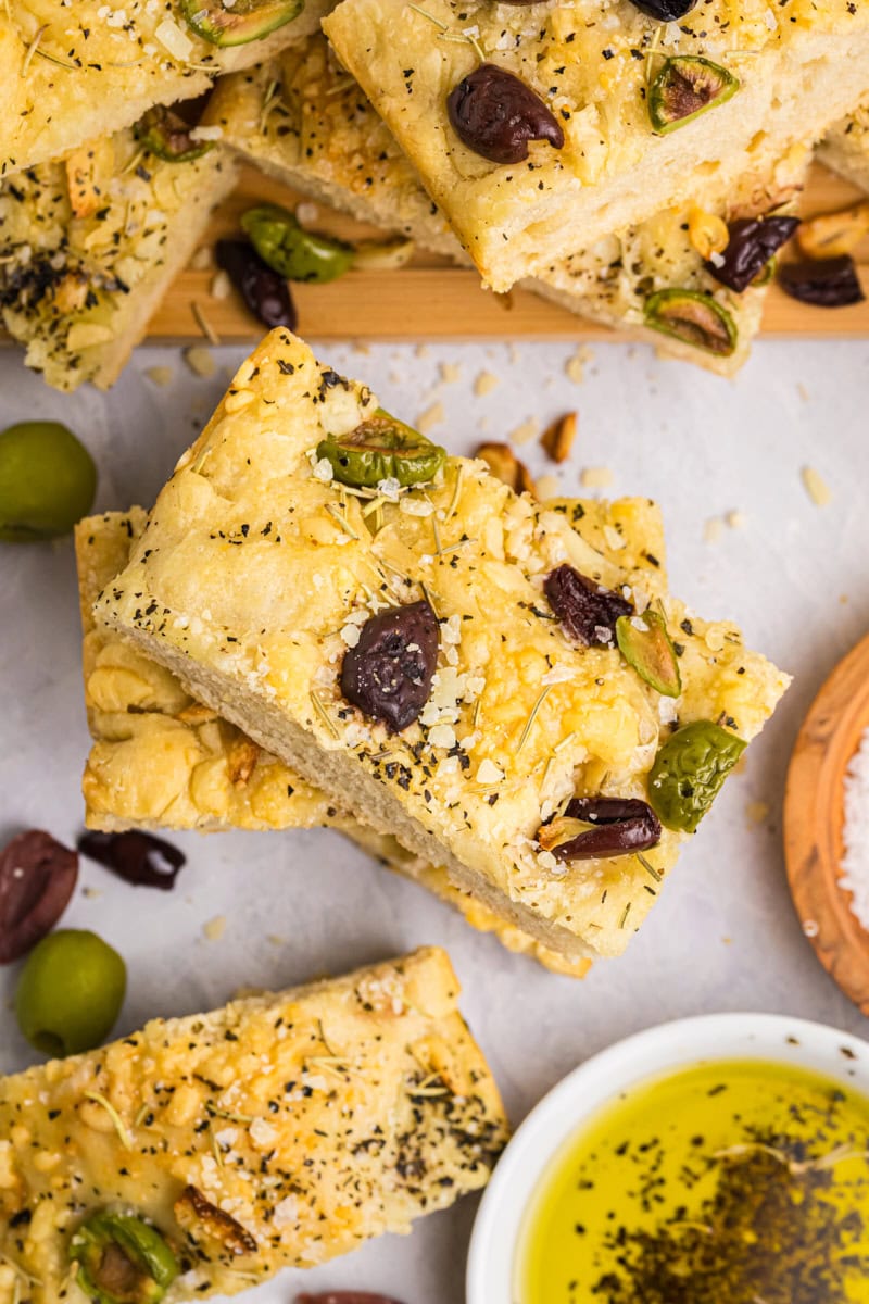 overhead view of a slice of no-knead focaccia topped with herbs, cheese, and olives