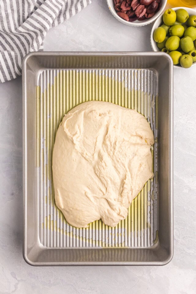 overhead view of no-knead focaccia dough in an oiled baking pan