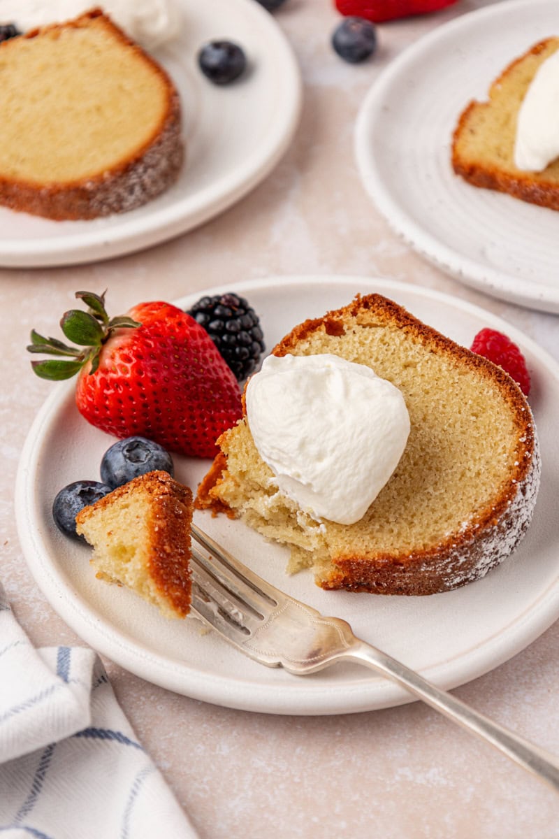 a slice of buttermilk pound cake topped with sweetened whipped cream and fresh berries
