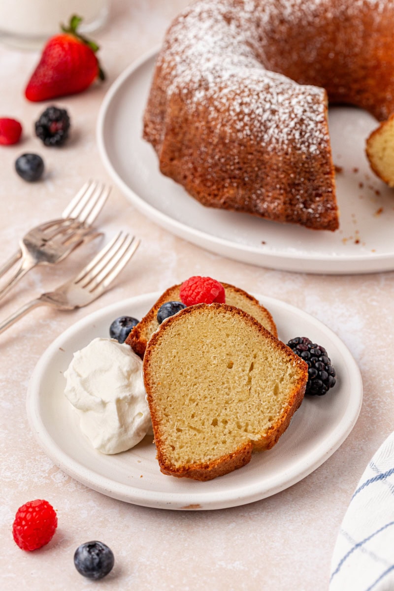 two slices of buttermilk pound cake served with whipped cream and fresh berries on a white plate