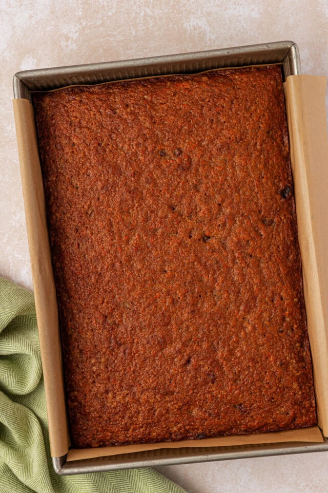 overhead view of freshly baked carrot sheet cake in a parchment-lined baking pan