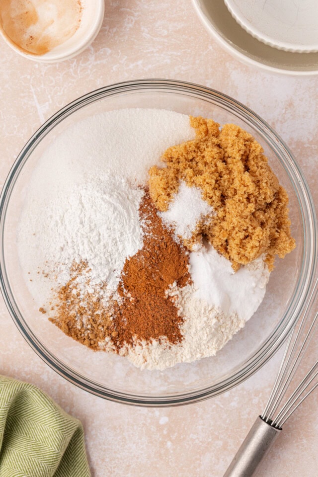 overhead view of flour, sugar, brown sugar, baking powder, baking soda, and spices in a mixing bowl